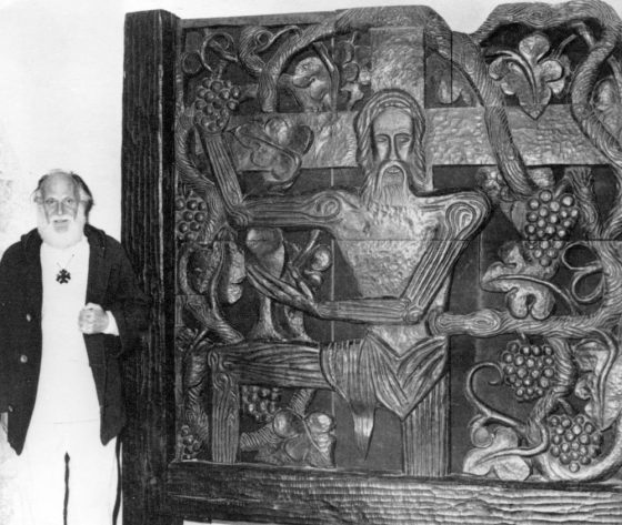 Lanza del Vasto posa delante de su escultura: el Cristo con vid